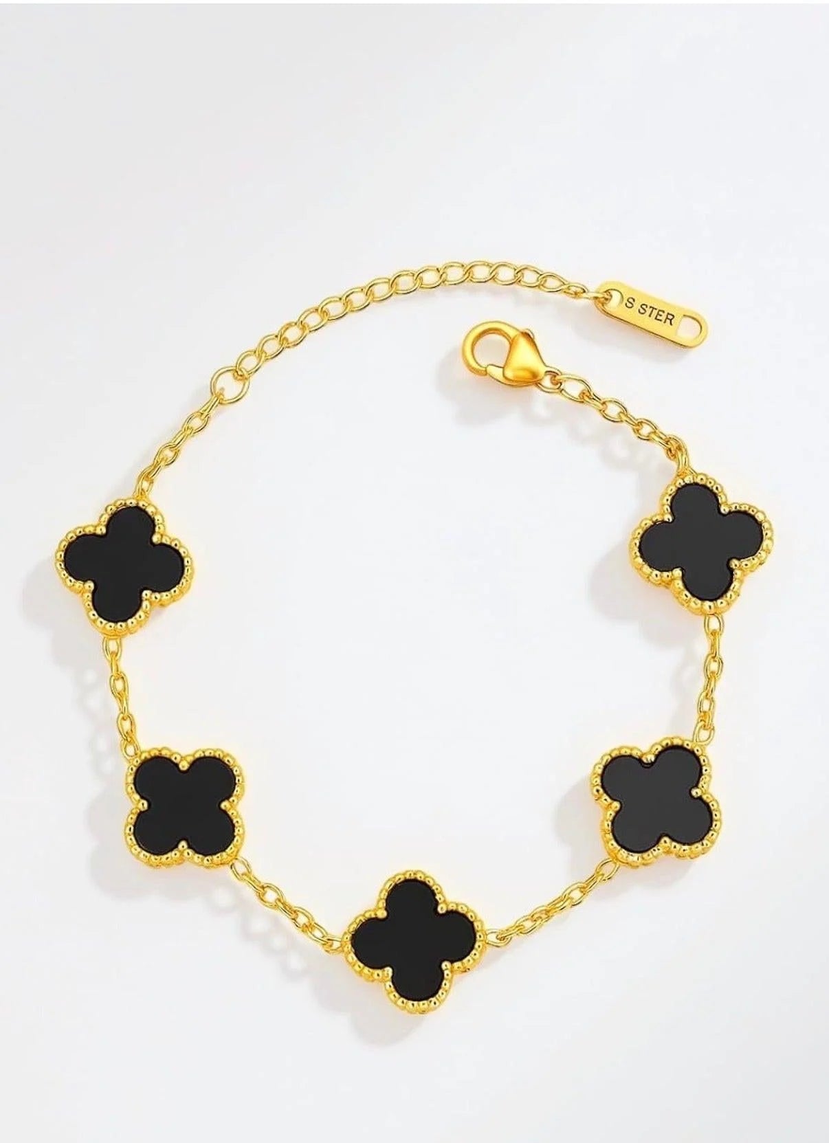 Gold bracelet with black clover-shaped charms on a white background