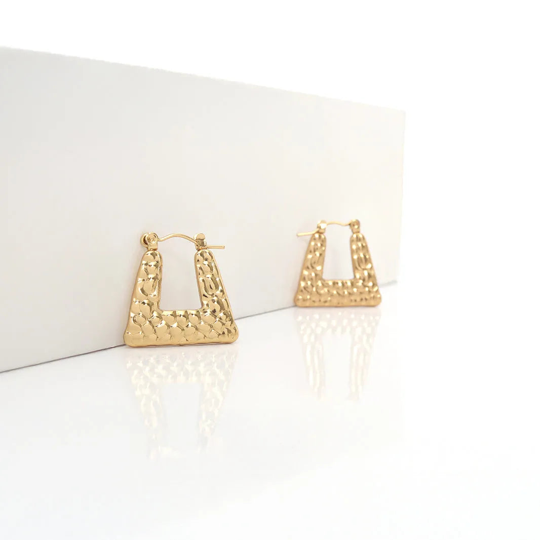 Gold hoop earrings with textured design on a white background