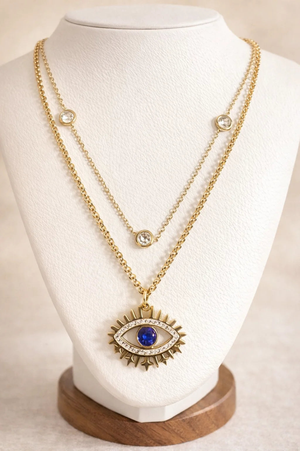 Gold necklace with an eye-shaped pendant on a mannequin bust.