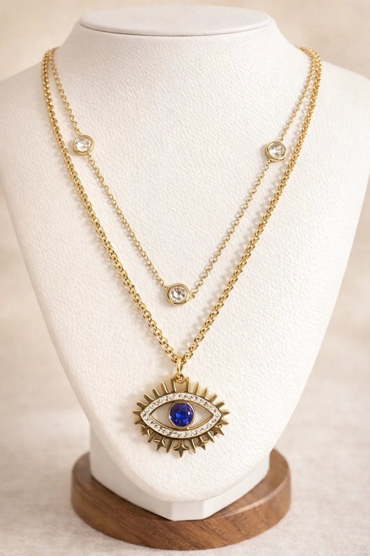 Gold necklace with an eye-shaped pendant on a mannequin bust.