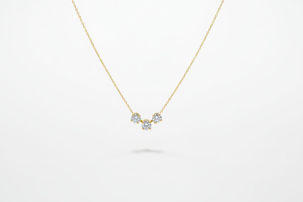 Gold necklace with three small gemstones on a white background