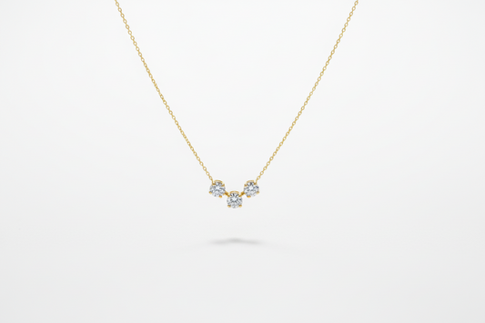 Gold necklace with three small gemstones on a white background