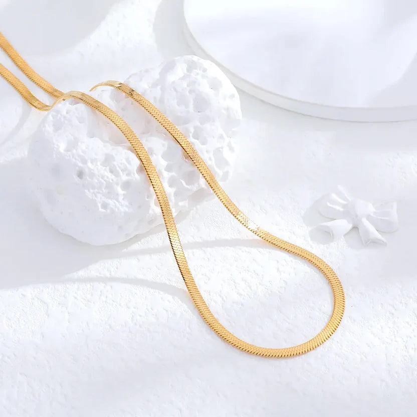 Gold chain necklace on a textured white surface