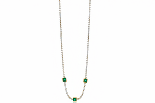Necklace with emerald green gemstones on a white  surface