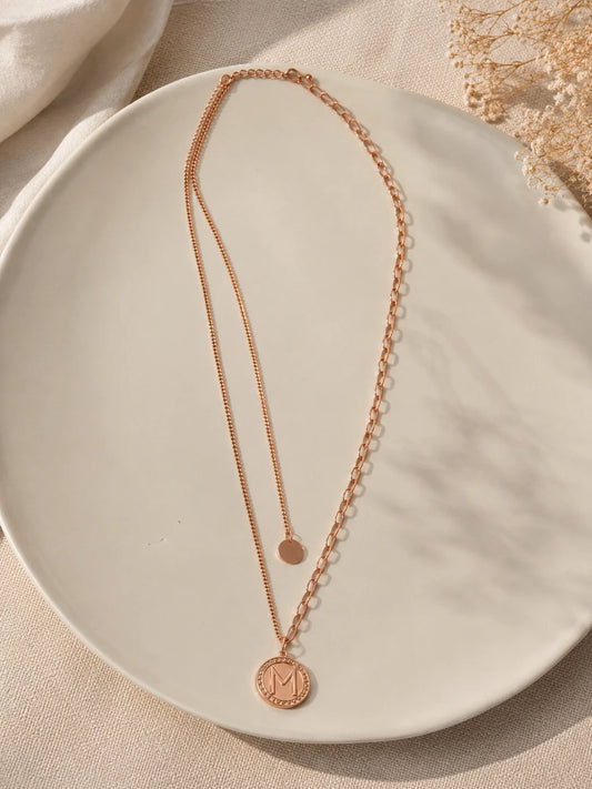 Rose gold necklace with circular pendants on a beige plate