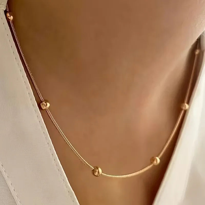 Gold necklace with small beads on a soft brown background