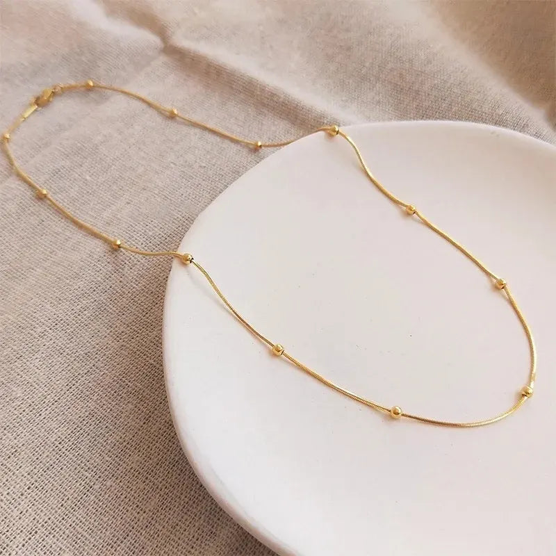 Gold necklace on a white plate with a beige fabric background