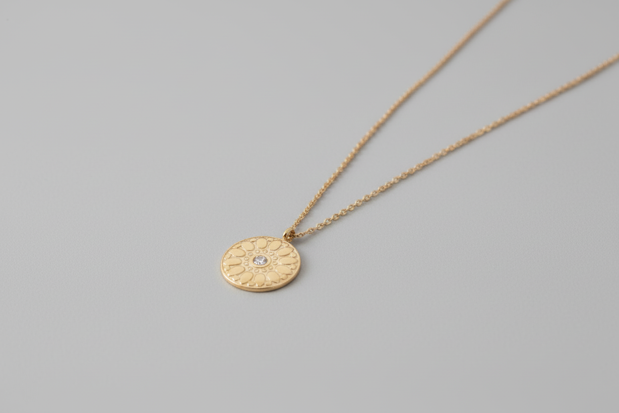 Gold necklace with a circular pendant on a stone surface