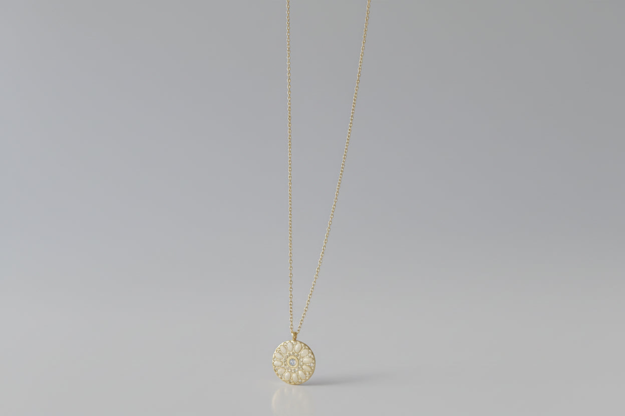 Gold necklace with a floral pendant on a gray background